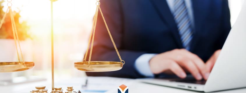 lawyer on computer with scales of justice on the desk